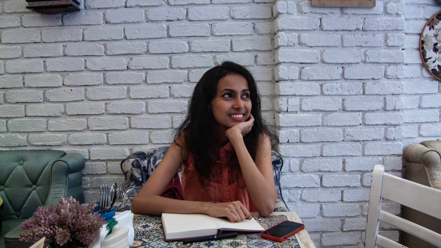 Shruti Prabhu seated at a table with a notebook